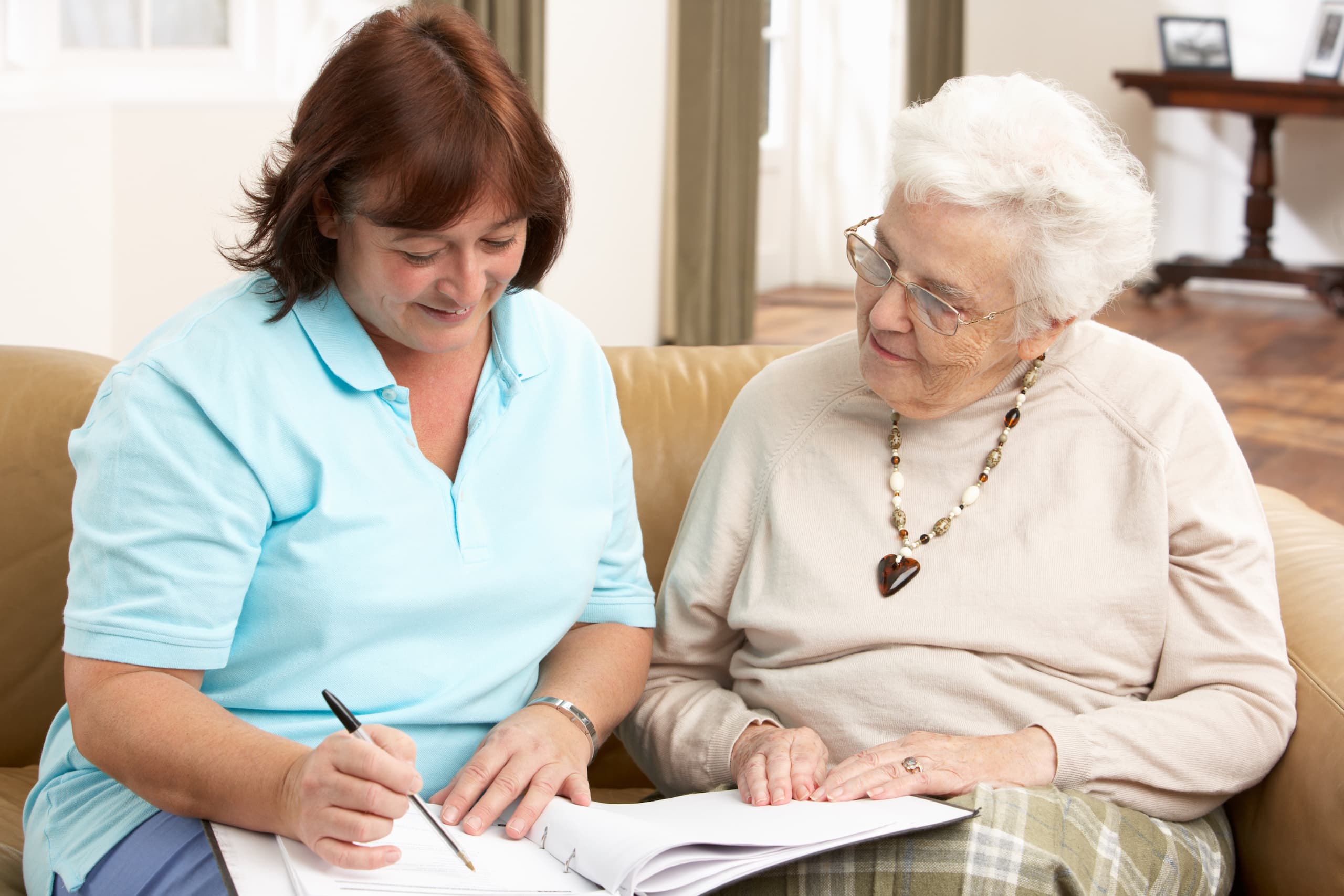 caregiver and elderly woman reviewing a book